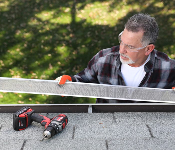 Man with safety glasses installing seamless gutters