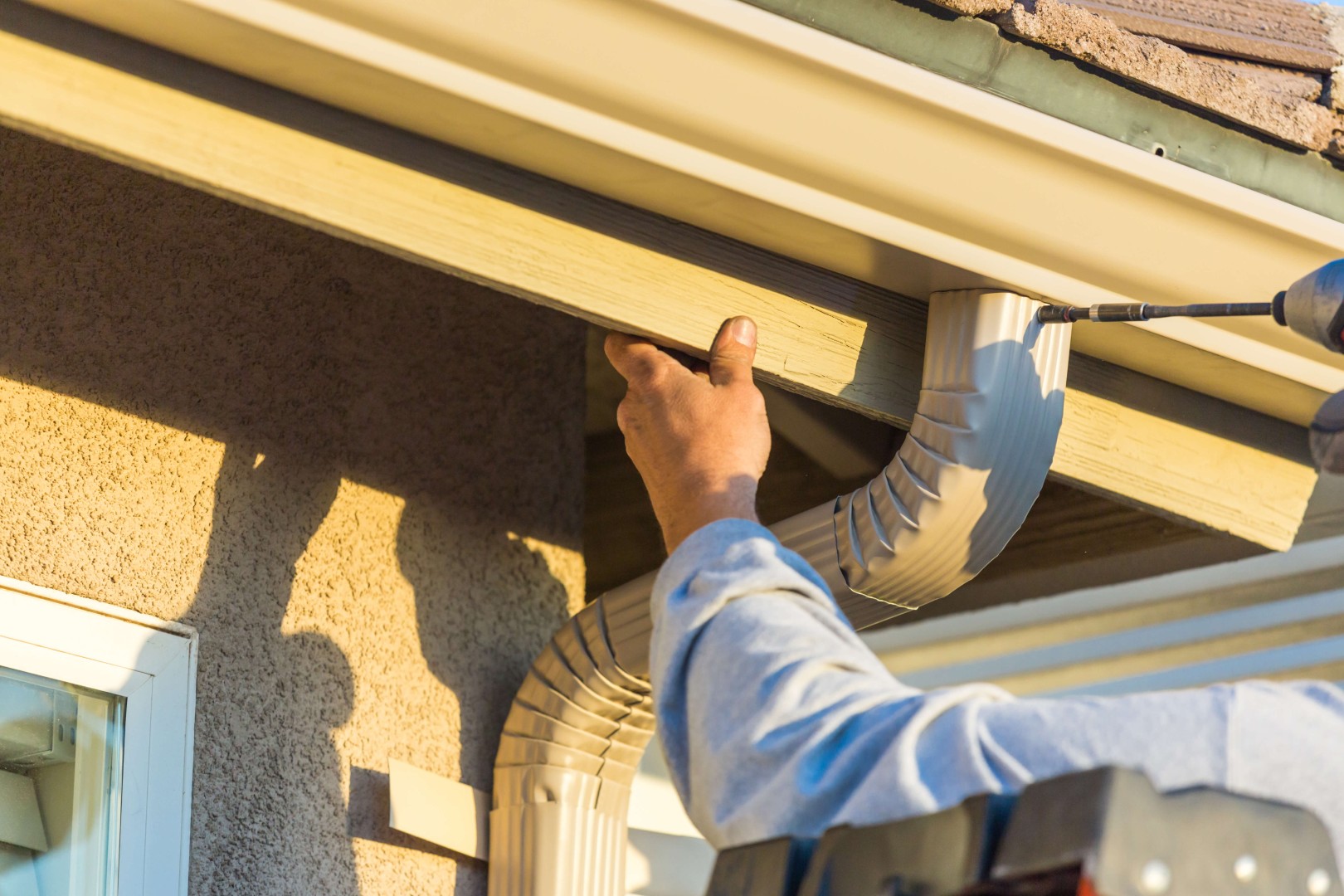 man installing a downspout on a roof gutter